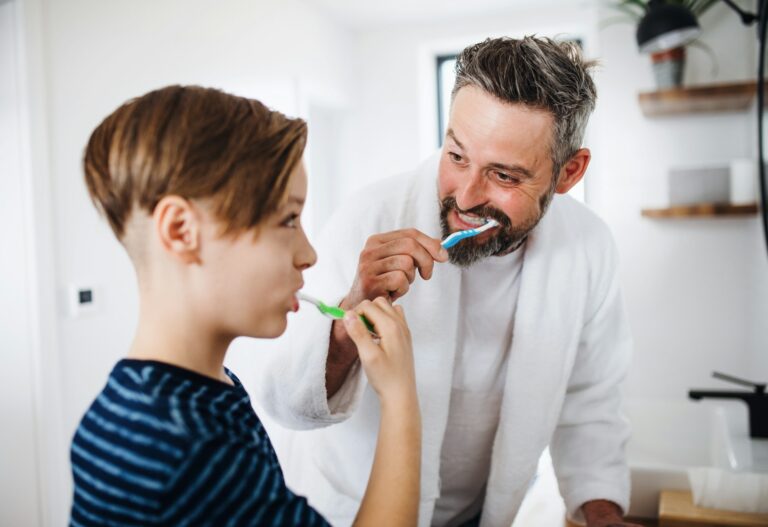 father and son brushing teeth