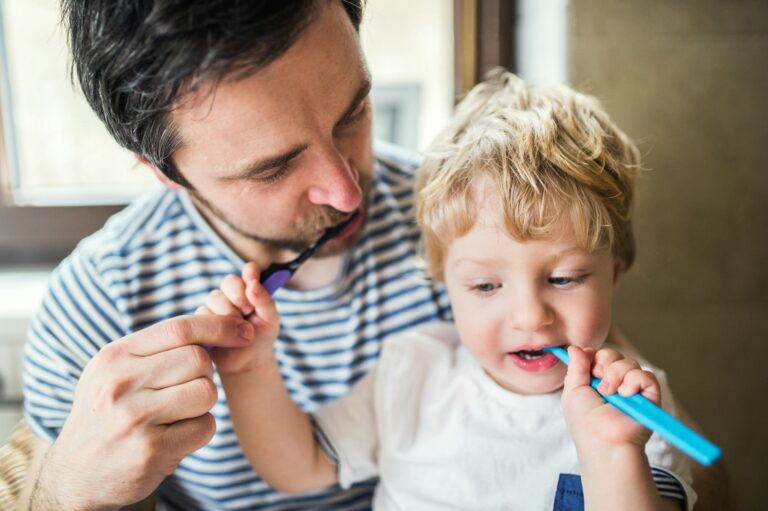 father and son brushing teeth